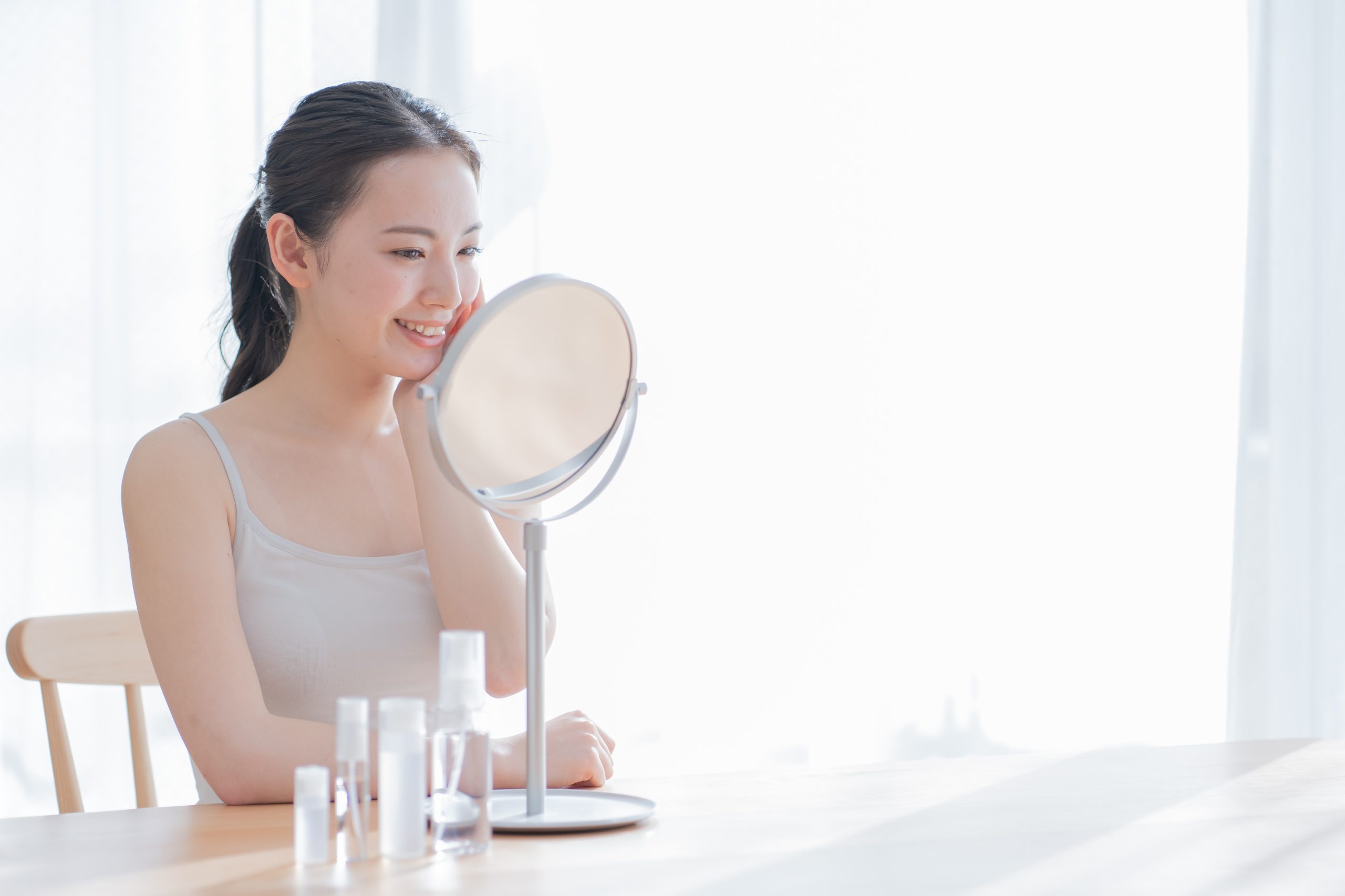 頬に手を当て、鏡を見ている女性の様子。